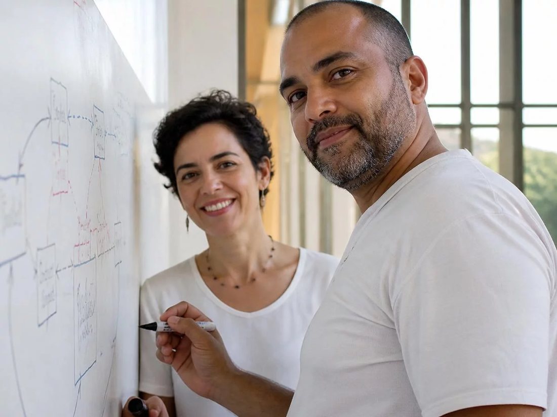 Duas pessoas diante do quadro branco com a armação de um argumento rabiscada